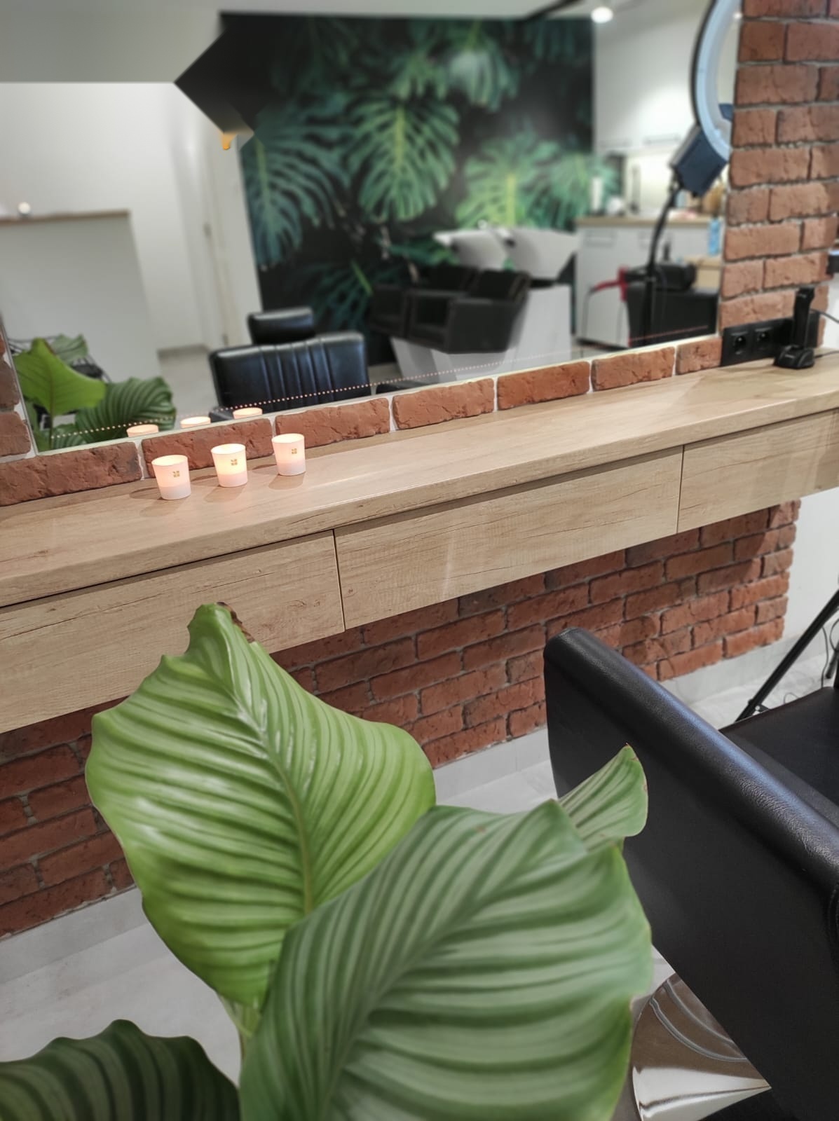 Detal wnętrza salonu — lustro, świece i zielone rośliny